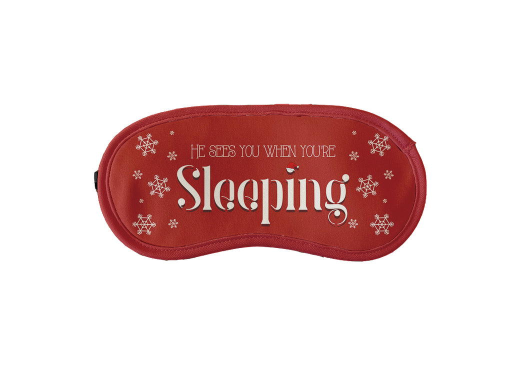 Red Christmas sleeping mask with festive text 'He sees you when you're sleeping.' for a holiday-themed sleep accessory.