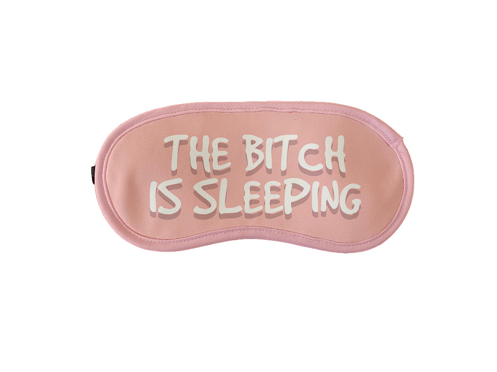 Peach coloured sleeping mask with humorous text 'The bitch is sleeping.' for a stylish and comfortable sleep accessory.